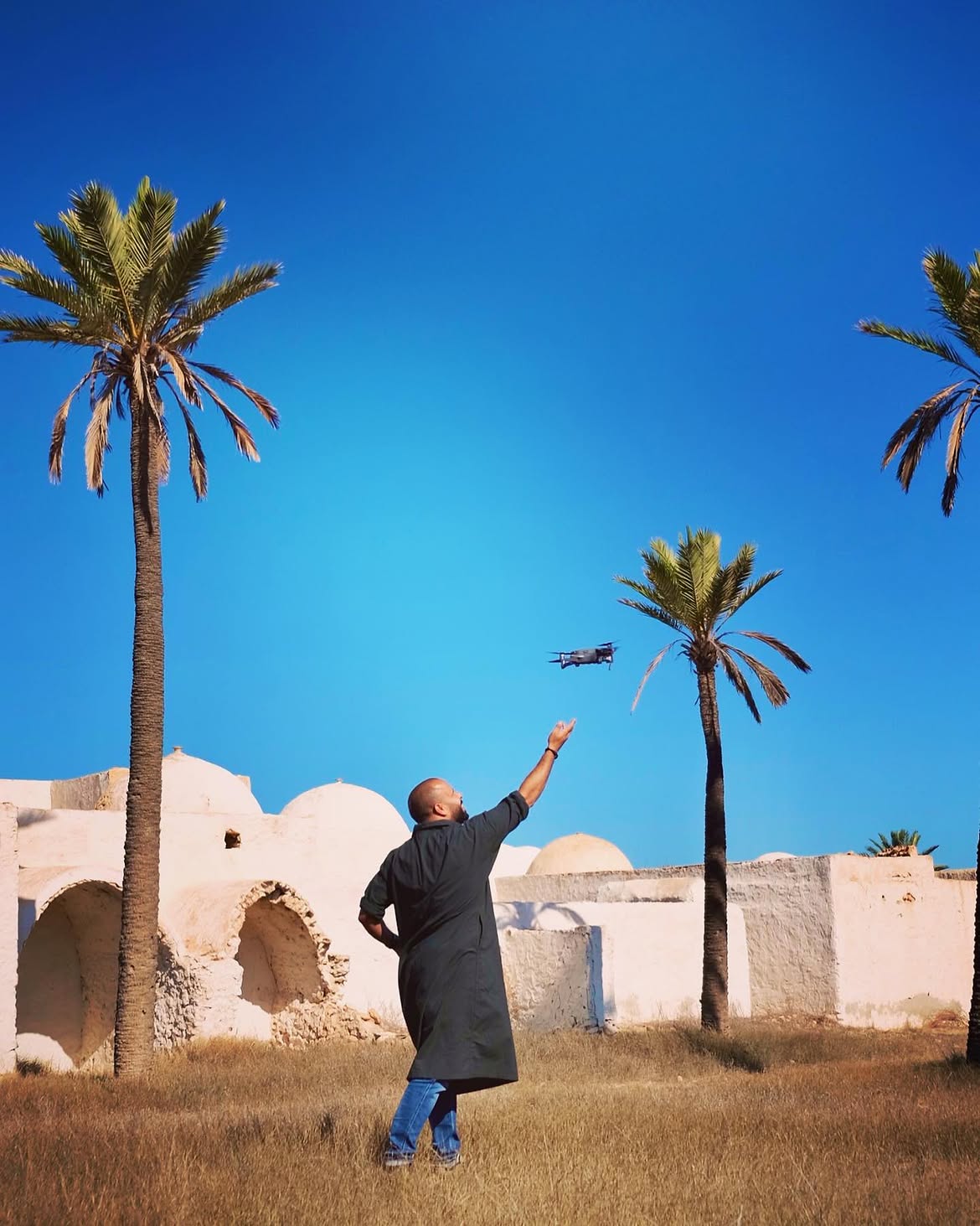 Traveler beneath palms and old architecture