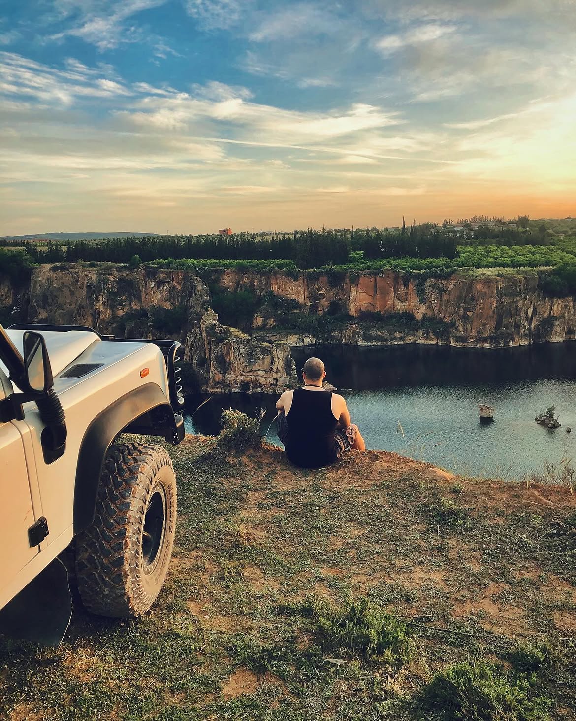 Rabii seated beside a vehicle, looking across a landscape