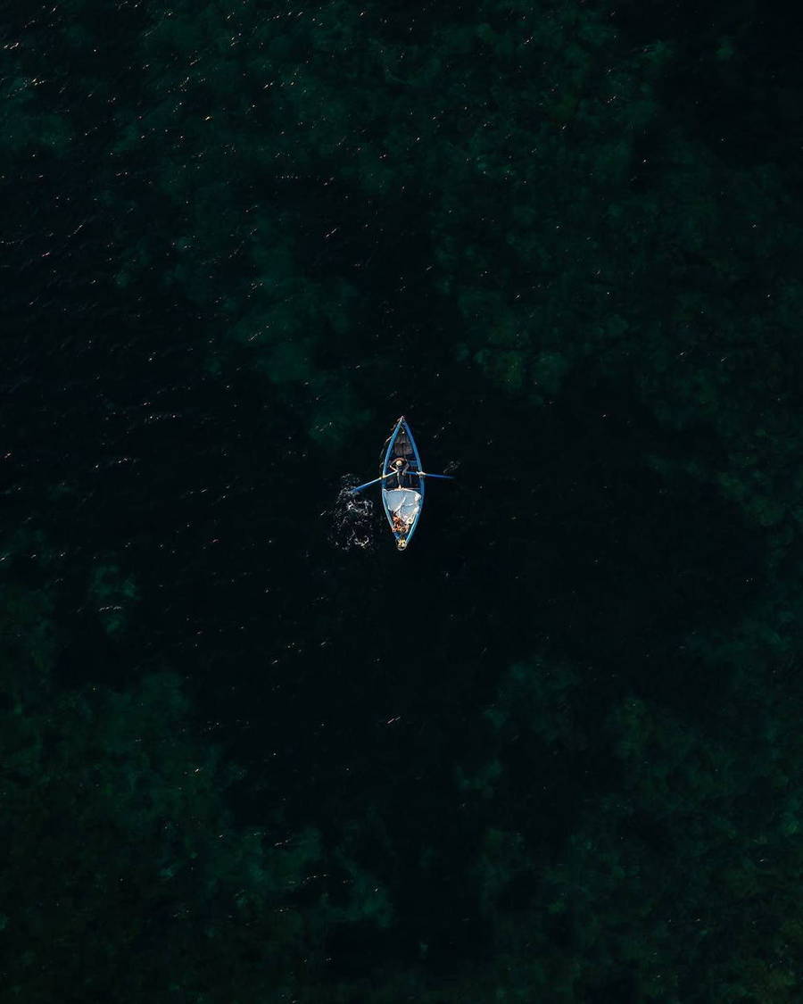 Single kayak on deep blue water seen from above