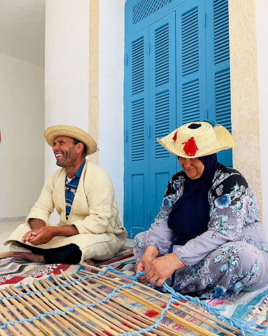 Two people seated beside bright blue doors