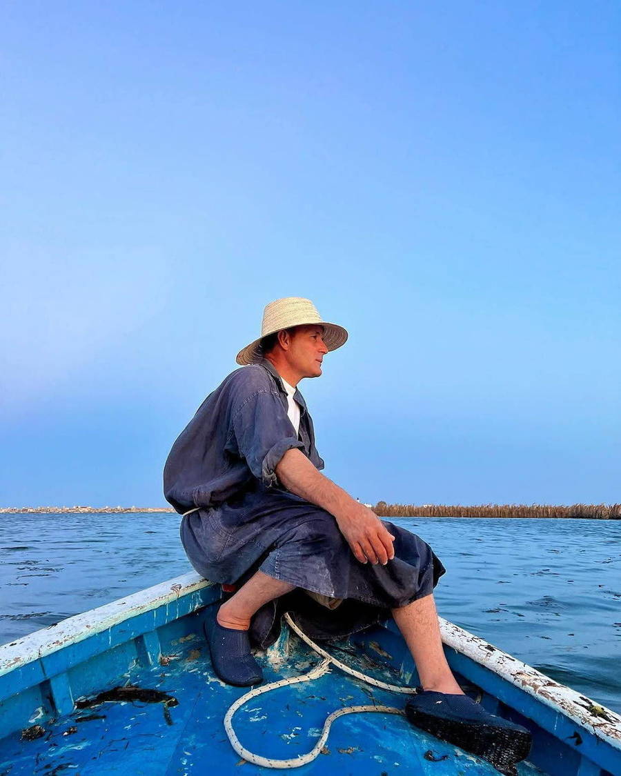 Fisherman seated on a blue boat at sea