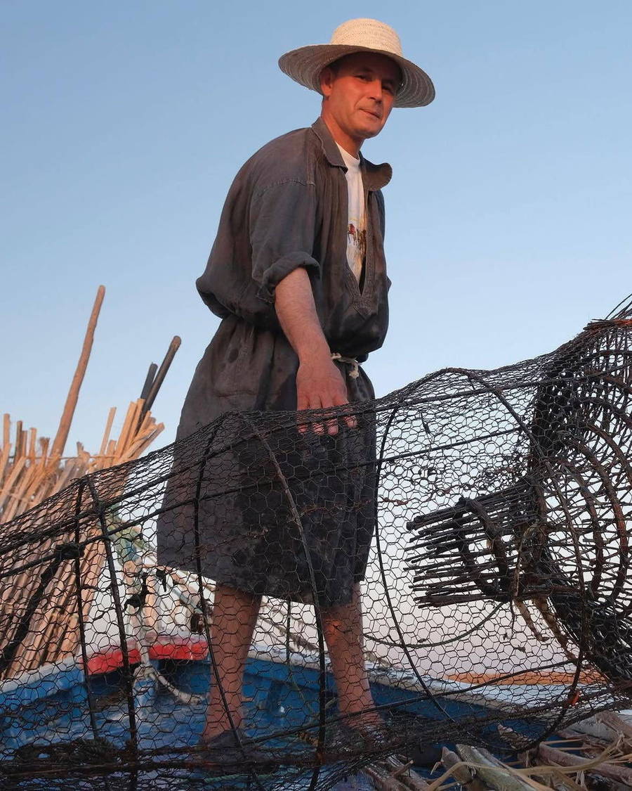Fisherman beside fishing nets under a tree
