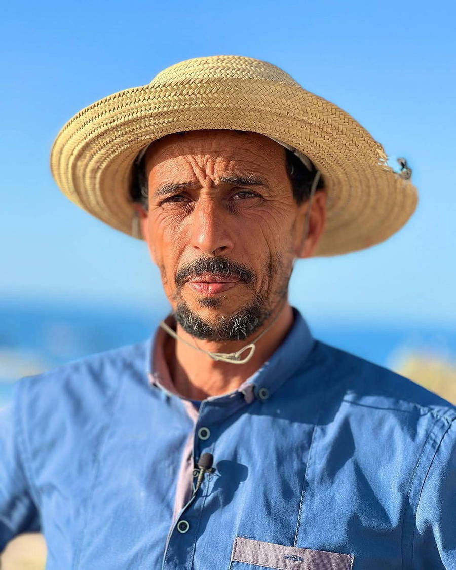 Portrait of Rabii wearing a straw hat beside the sea