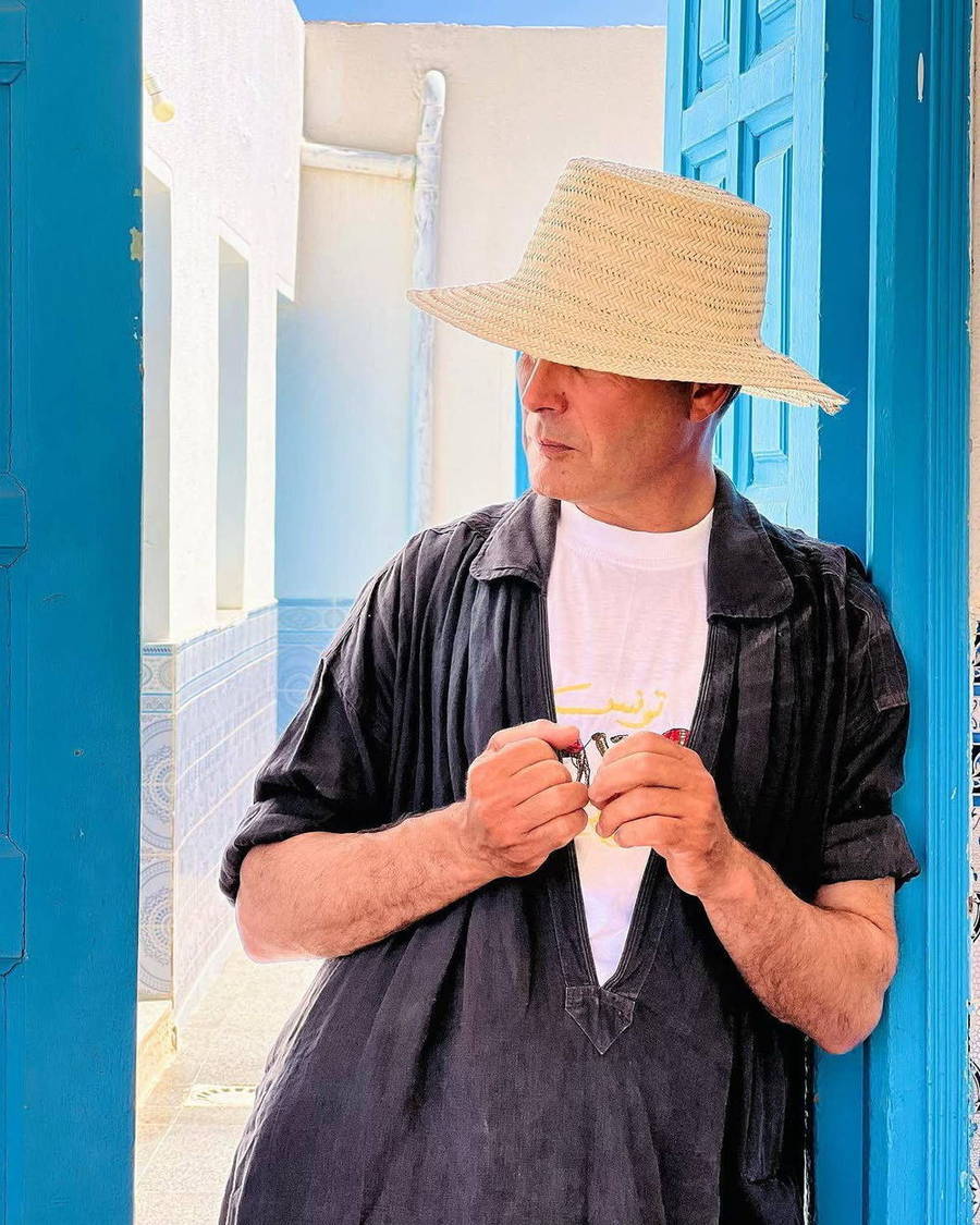 Rabii wearing a straw hat beside a blue doorway
