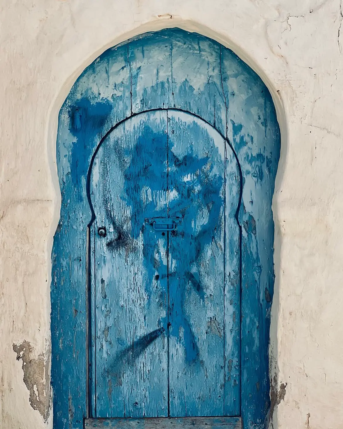 An old blue doorway in a pale stone arch