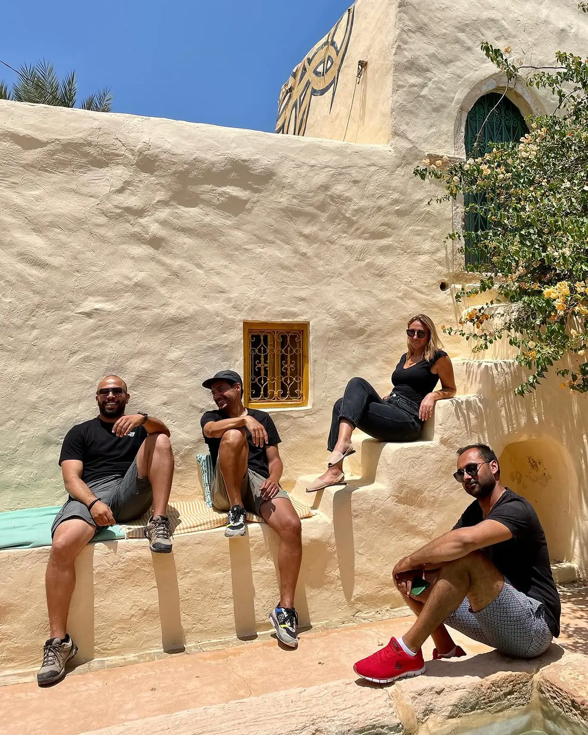 The group rests together beside a whitewashed building