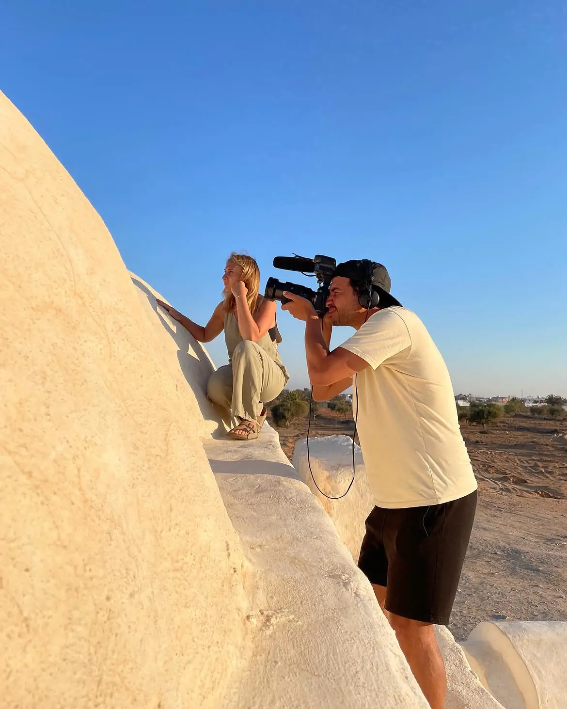 A filmmaker takes a portrait beside a pale stone wall